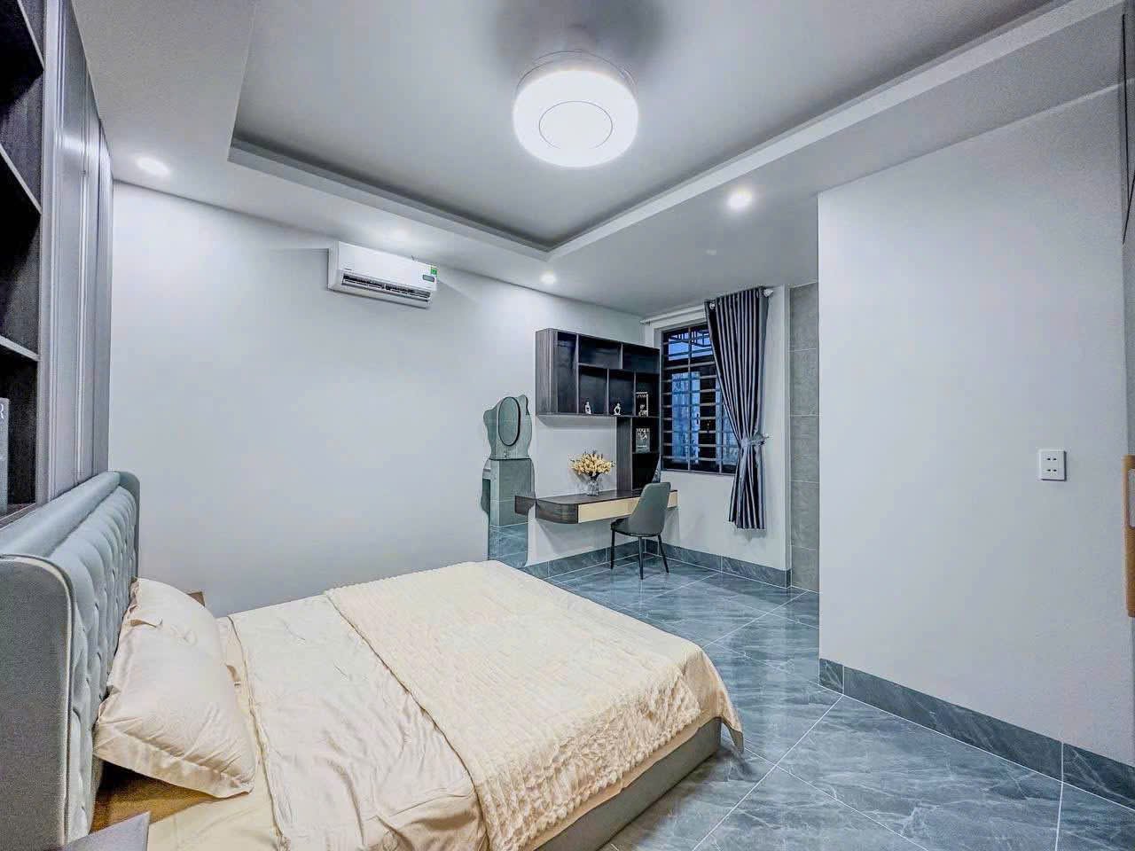 Bàn nhỏ kết hợp kệ treo được đặt cạnh cửa sổ của phòng ngủ.